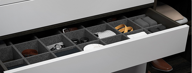 Tiroir ouvert avec compartiments organisant ceintures, lunettes, montres, et vêtements pliés, dans une structure blanche et grise.
